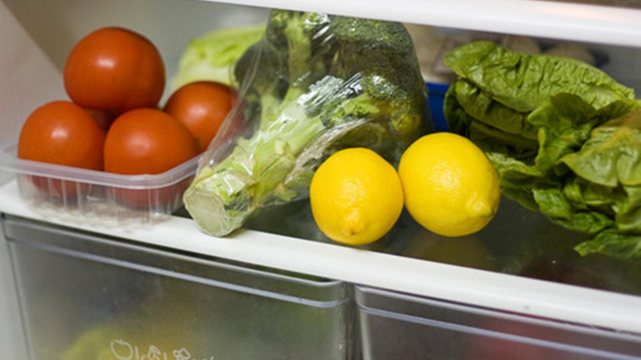 Hylde i køleskab fyldt med grøntsager.