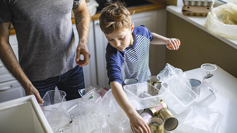Dreng sorterer plastikemballage i køkken med sin far