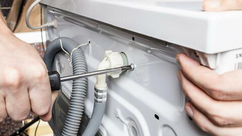 Mand skruer ledning og vandtilførsel ud af vaskemaskine
