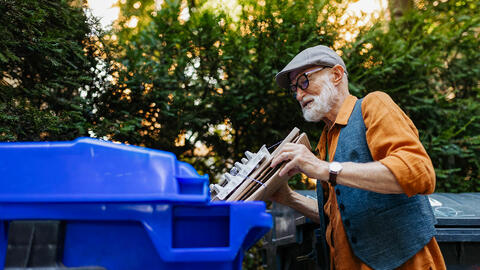 Ældre mand med gråt skæg sorterer papaffald