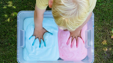 Dreng med hænderne i farvet skum