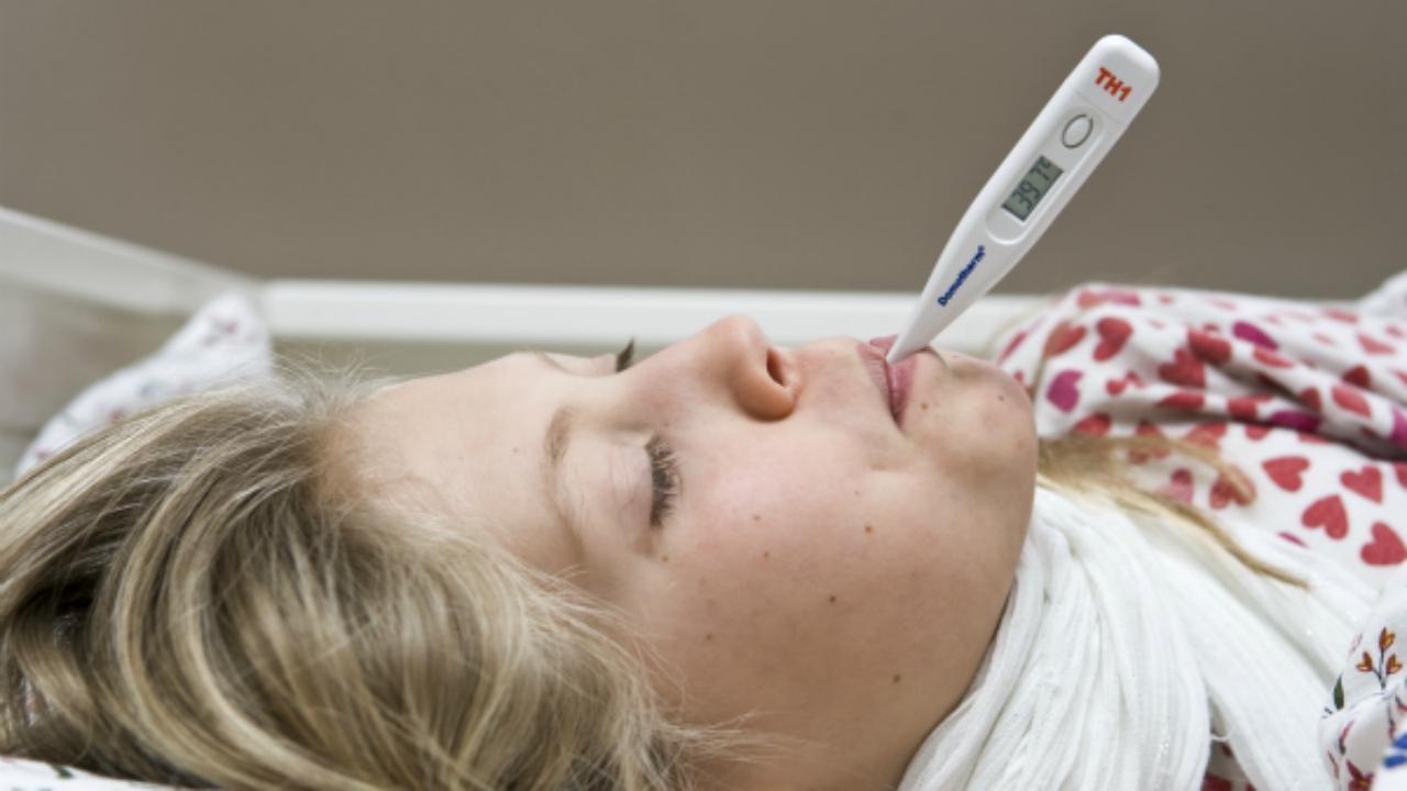 En kvinder ligger ned med et termometer i munden