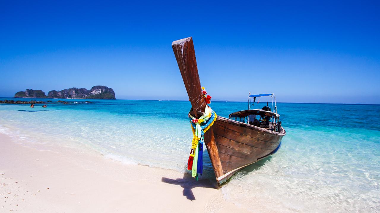 Flot thailandsk båd ligger på sandstrand