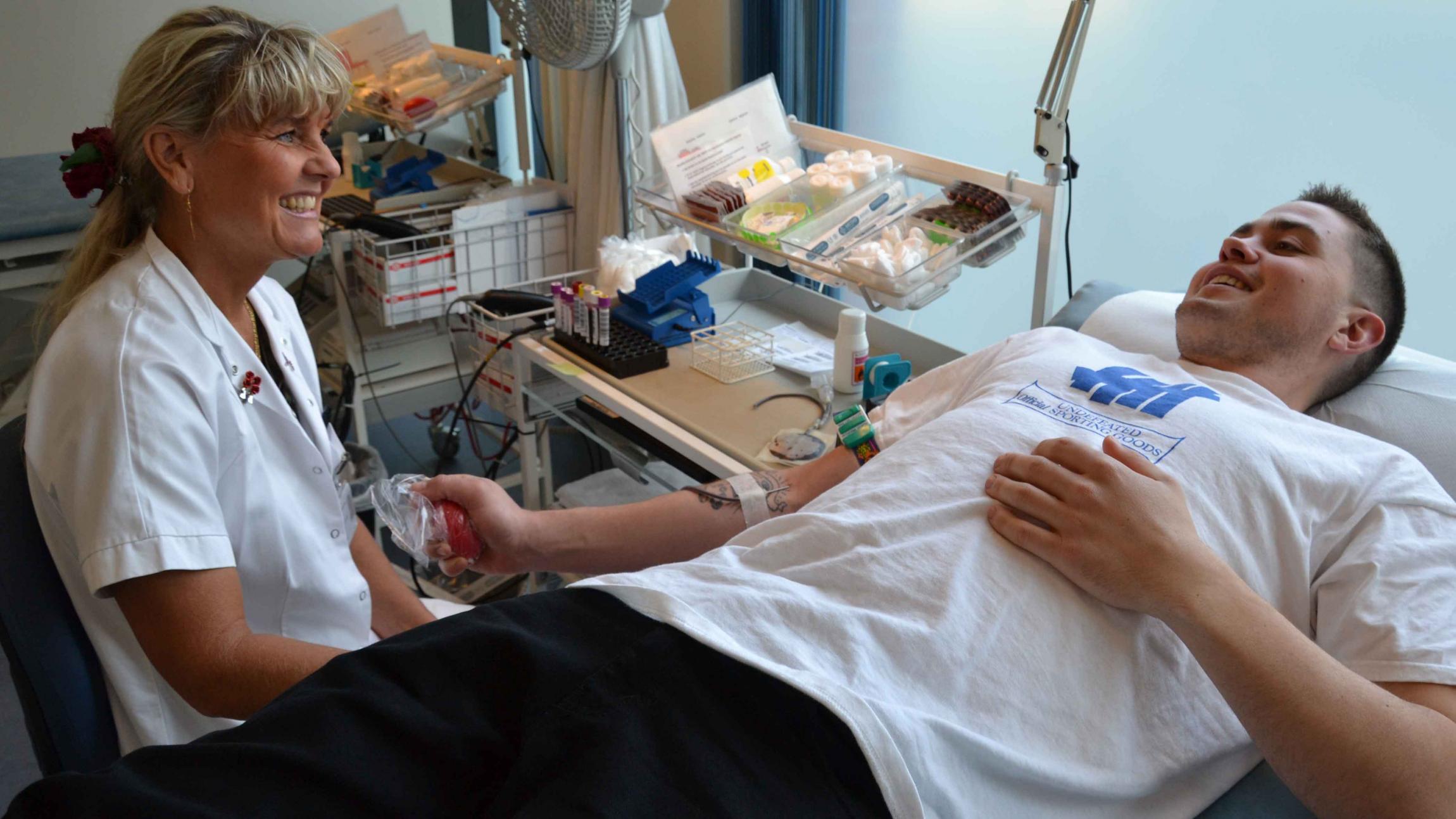 En mandlig bloddonor får tappet blod assisteret af en sygeplejerske