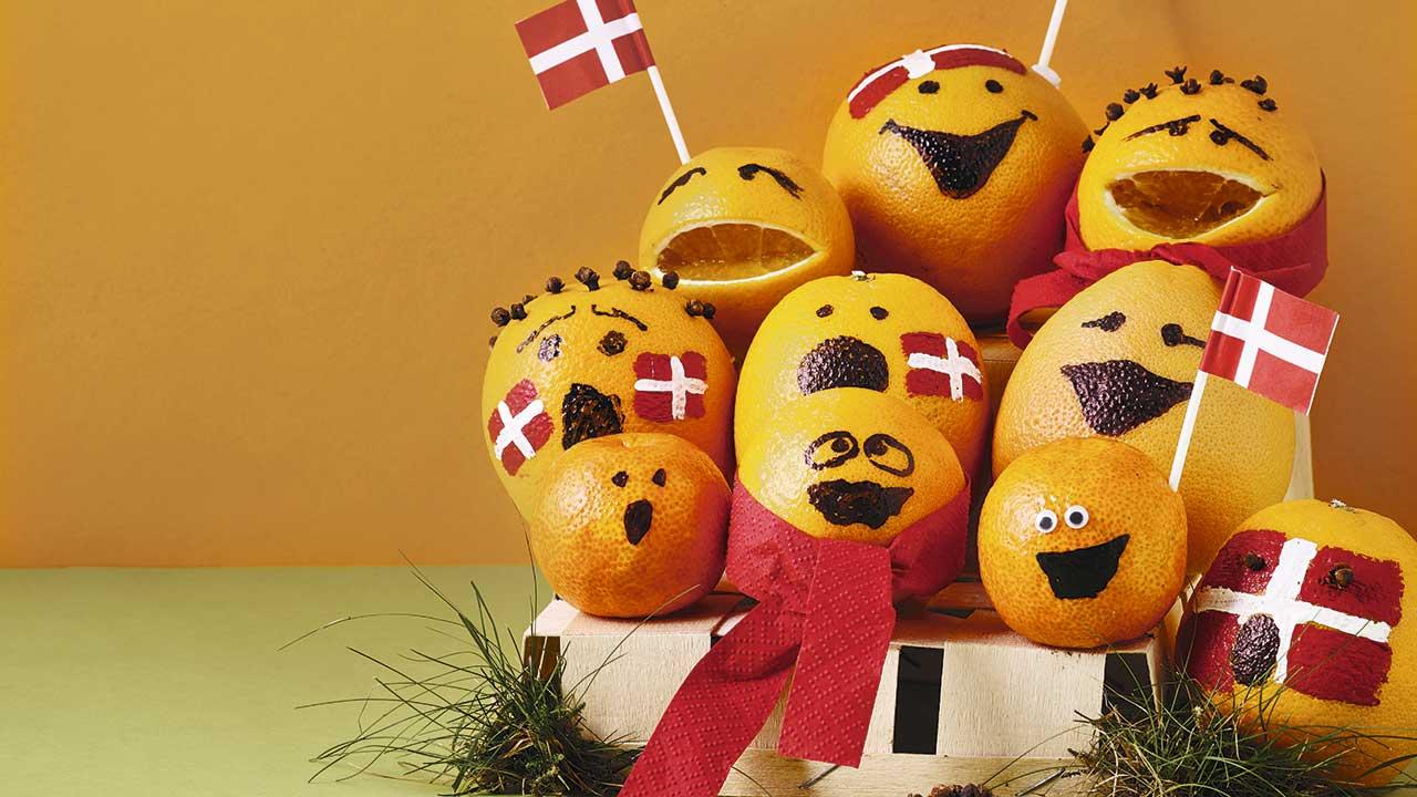 Appelsiner og clementiner med påtegnede munde synger i kor, mens de flager med danske flag