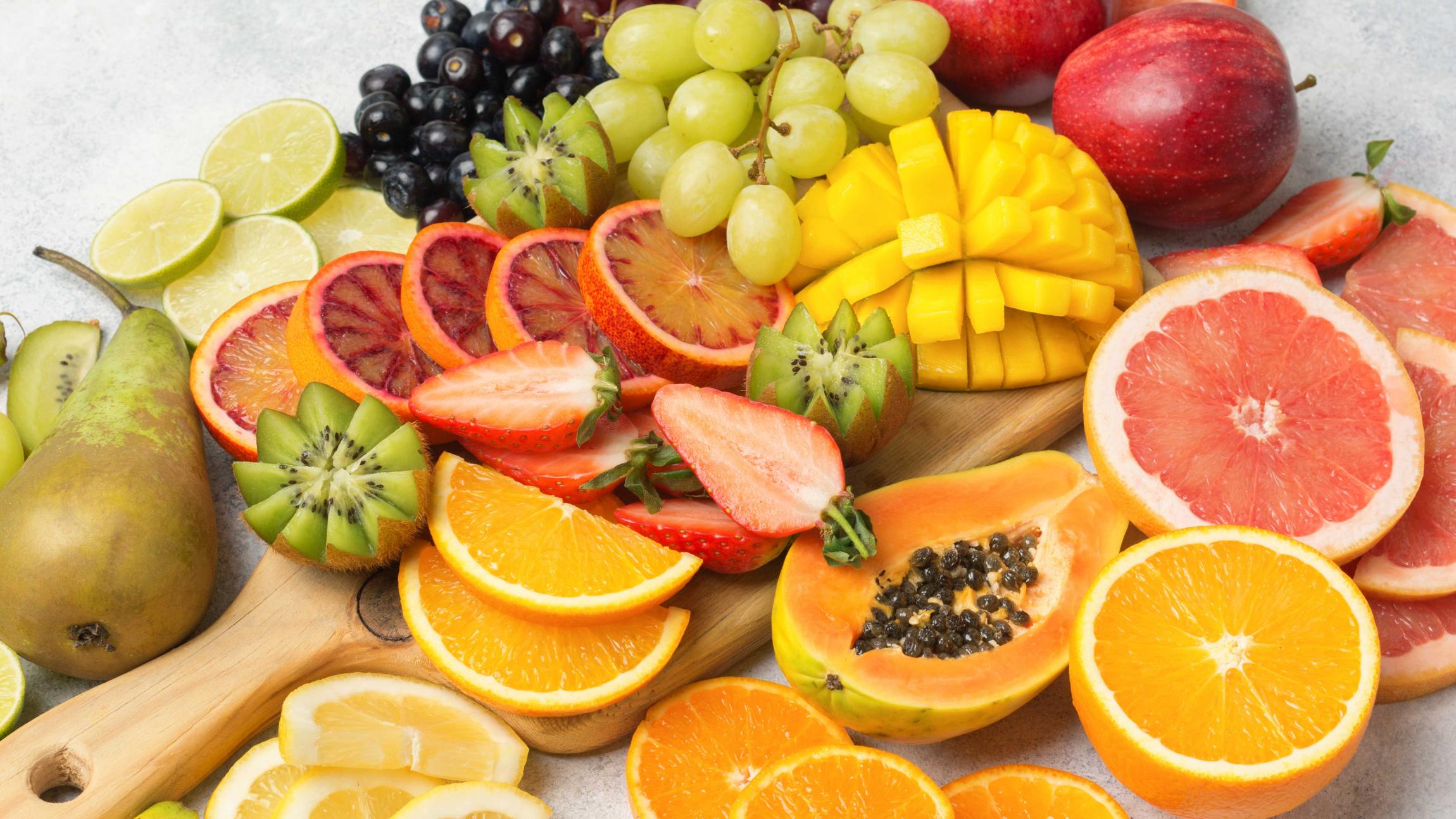 Frugtfad fyldt med en masse forskellige frugter såsom vindruer, appelsiner, pærer og ananas