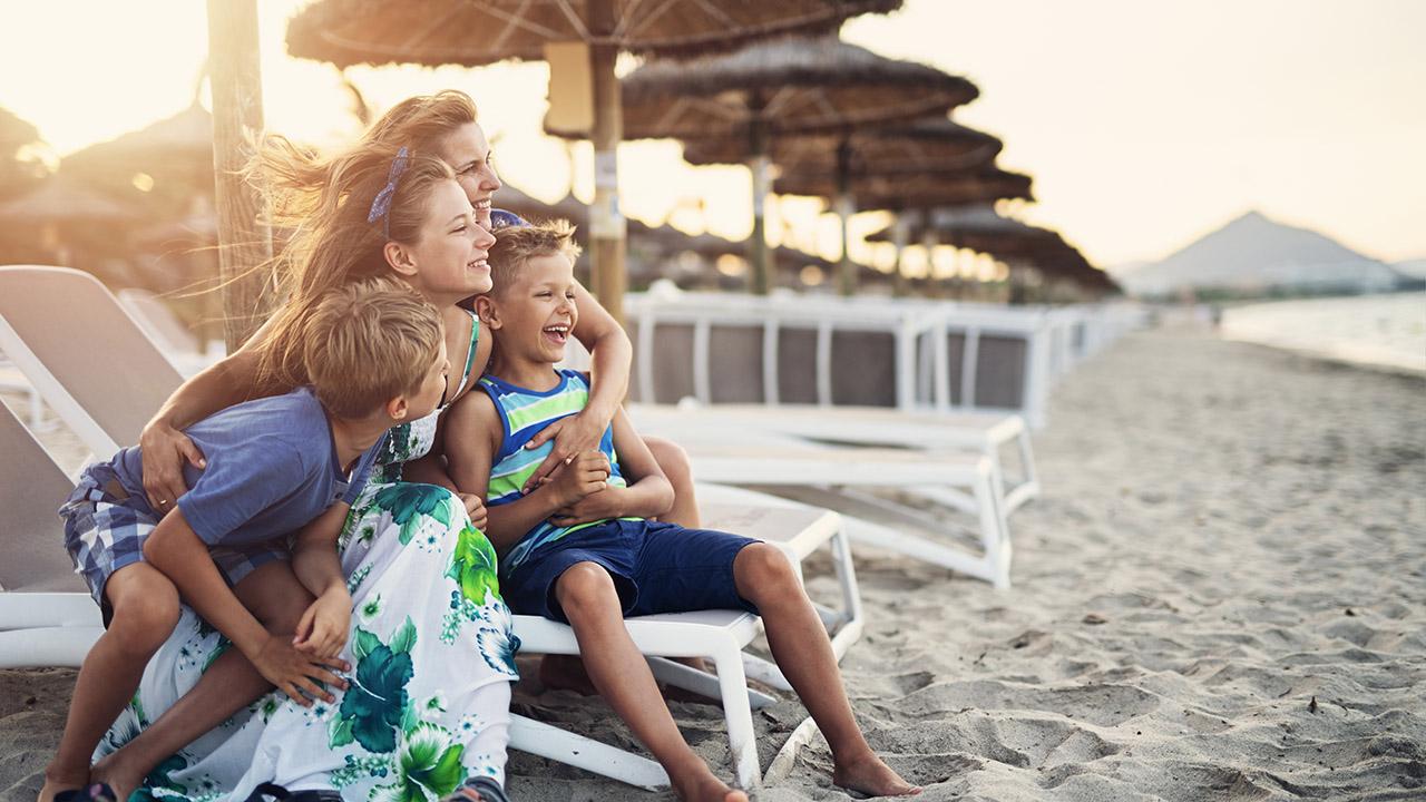 Familie på strand under parasoller