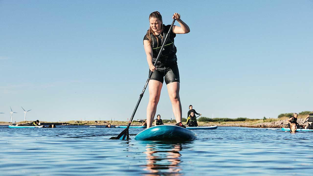 Kvinde står på SUP på Amager Strandpark