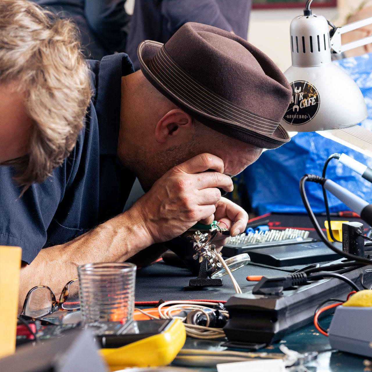 Frivillig på Repair Café nærstuderer elektronikudstyr gennem en lup