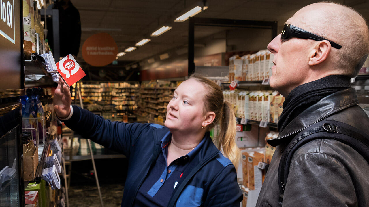Salgsassistent Lene Lorckmann viser Christian Bundgaard varer på supermarkedshylden.