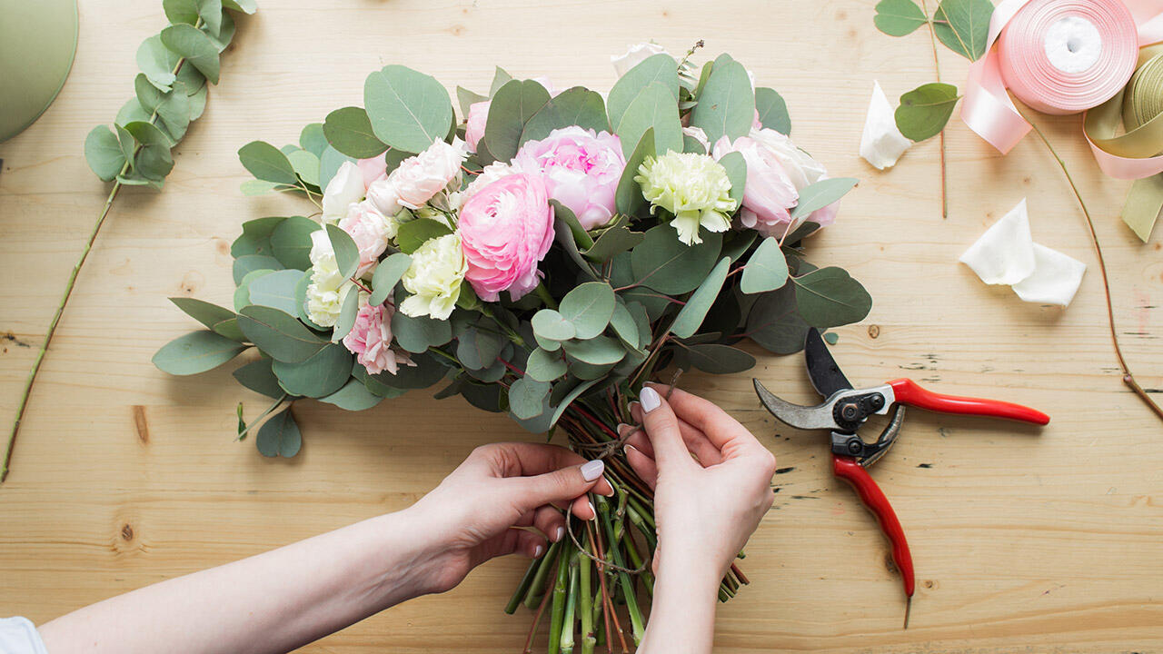 Blomster arrangeres og bindes på et bord