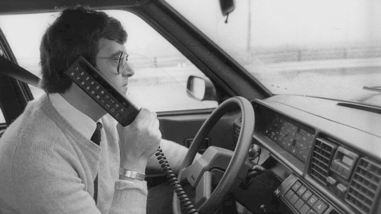 Mand taler i håndholdt telefon i bil
