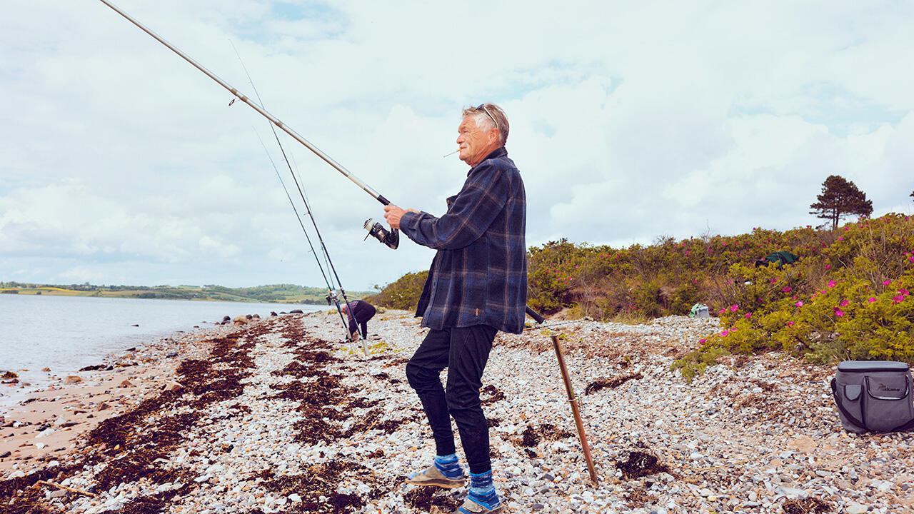 Mand med fiskestang på strand 