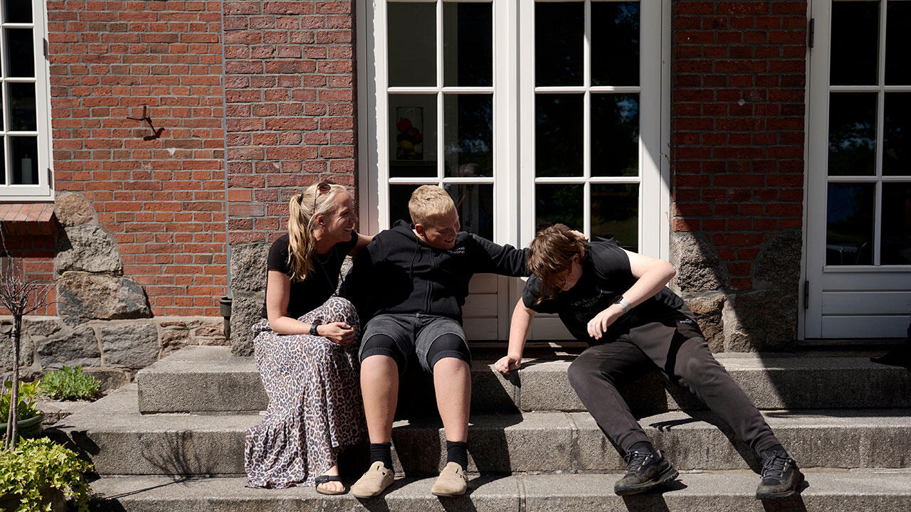 Lærer og to elever sludrer på trappen foran julemærkehjemmet Fjordmarkrk 