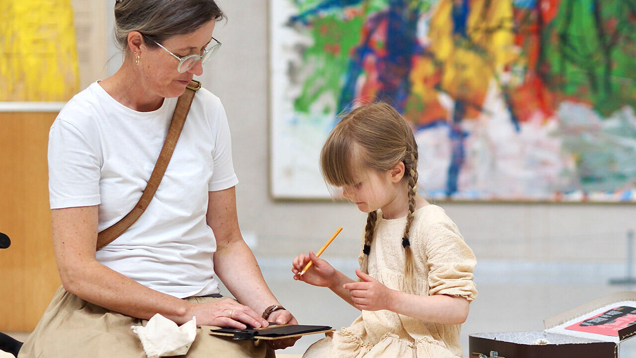 Kvinde og barn tegner på museum