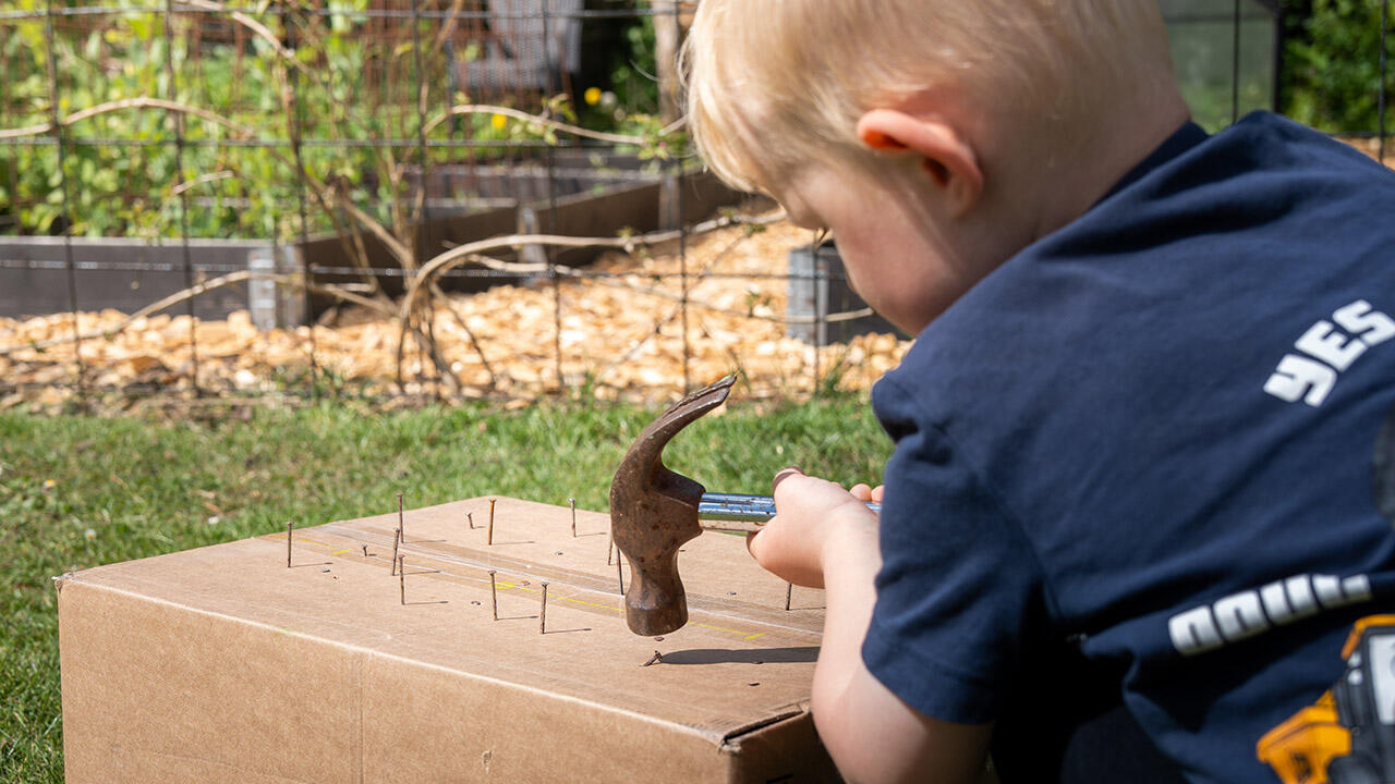 Dreng slår søm i papkasse 