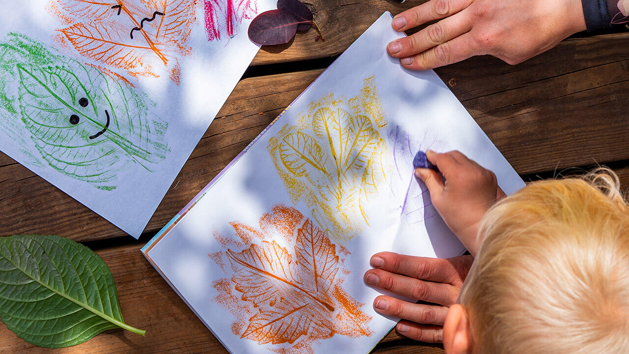 Barn laver bladaftryk med farvekridt 