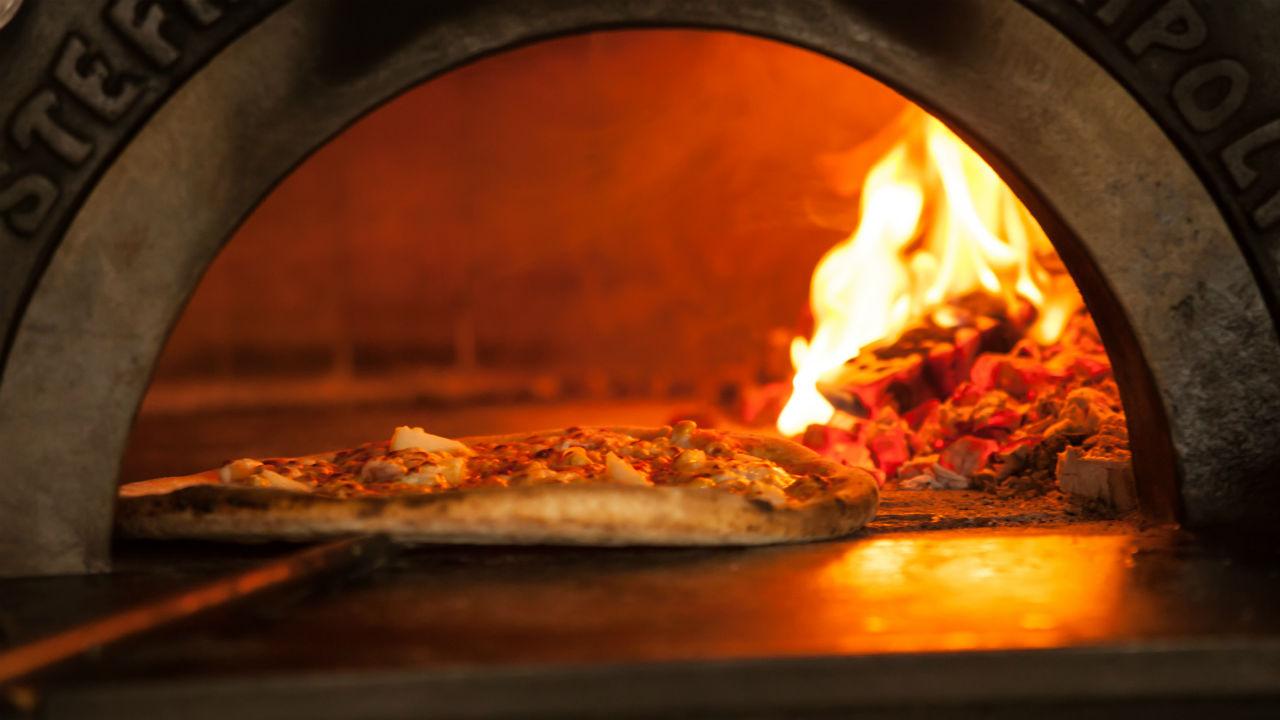 Pizza på vej ind i en brændefyret pizzaovn