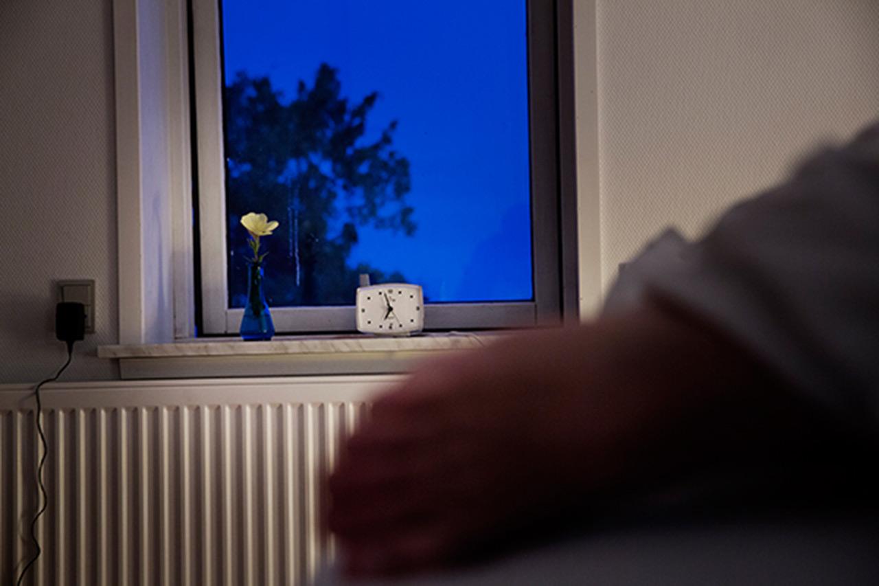 person foran vindue om aftenen.