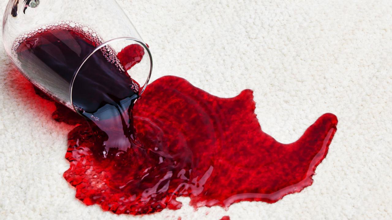 Væltet glas med rødvin på et tæppe