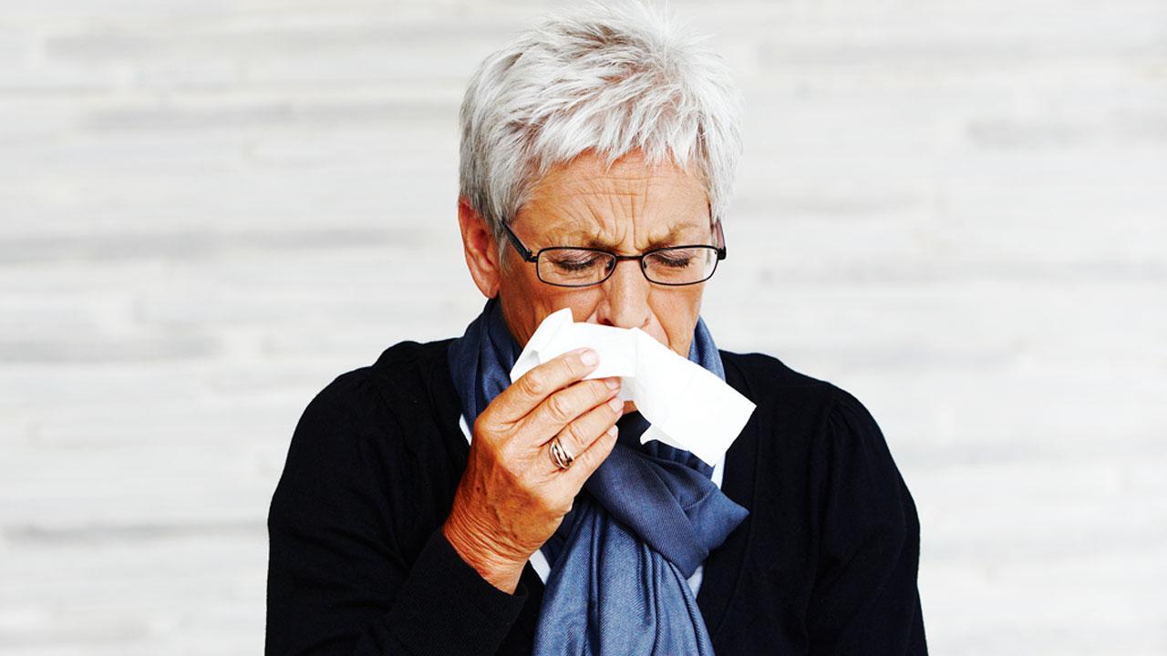 kvinde tørrer sig under næsen med papirsserviet
