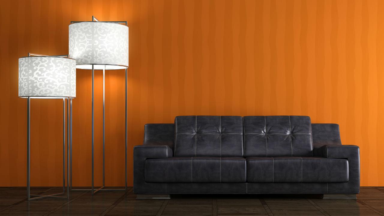 sofa og standerlampe op ad en orange væg.